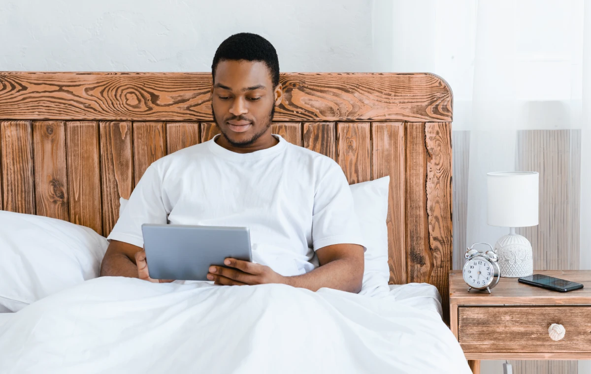 Man Relaxing in Bed Using a Tablet in a Cozy Bedroom
