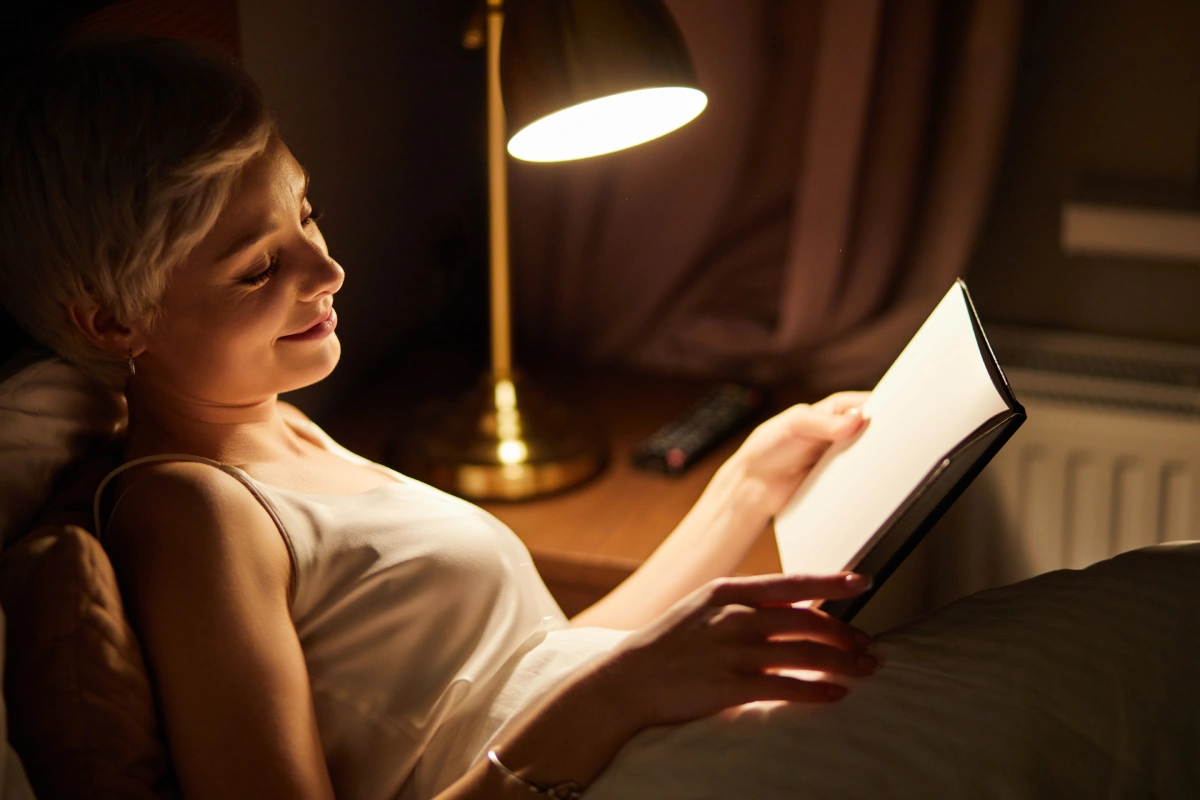 Woman Reading in Bed by Warm Lamp Light